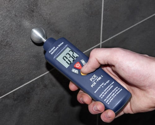 Das Materialfeuchte-Messger�t bei der Messung einer Wand mit Fliesen