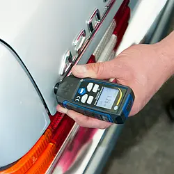 Comprobador de material haciendo una medición en un vehículo