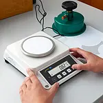Balanza de laboratorio midiendo el gramaje de un cartón